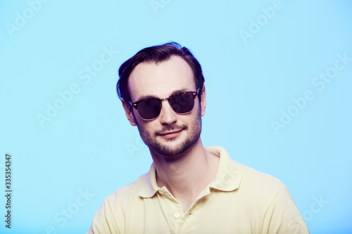 Studio shot of handsome man wearing sunglasses over blue background © sarymsakov.com