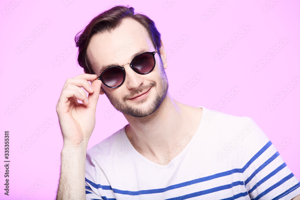 Studio shot of handsome man wearing sunglasses over pink background.