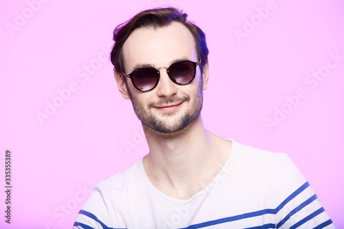 Studio shot of handsome man wearing sunglasses over pink background.