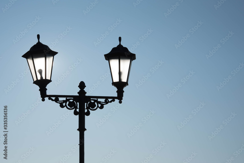 Street lamp with lamps in a classic style against a dark blue sky. Dark evening or night.