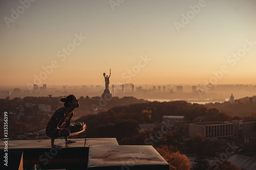 Woman doing yoga on the roof of a skyscraper in big city.