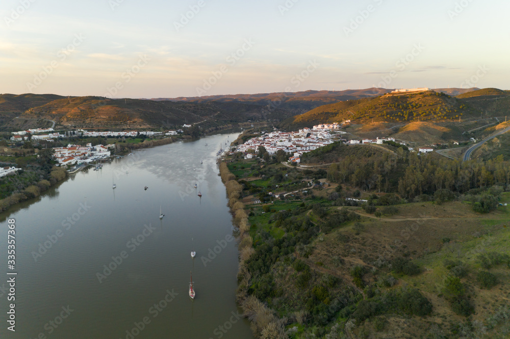 Aerial drone view of Sanlucar de Guadiana in Spain and Alcoutim in Portugal with sail boats on Guadiana river