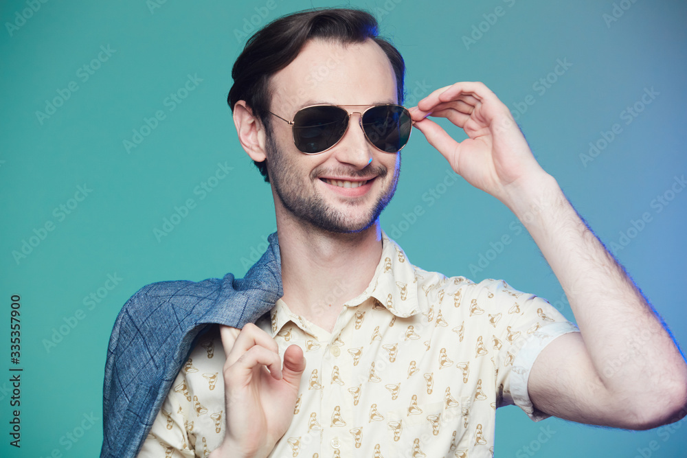 Studio shot of handsome man wearing sunglasses over green background.