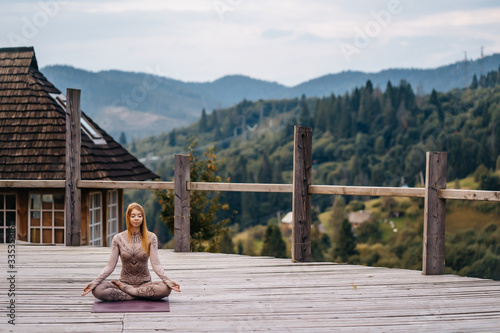 A woman sitting in lotus position at the morning on a fresh air. © teksomolika