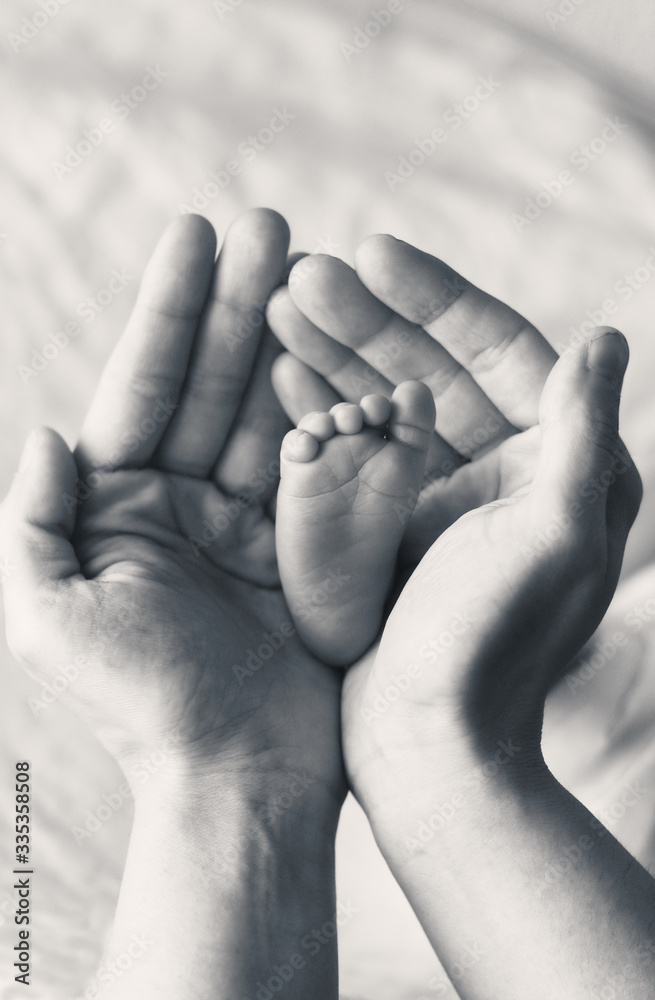 Fototapeta premium A baby's foot in his mother's hands safe at home