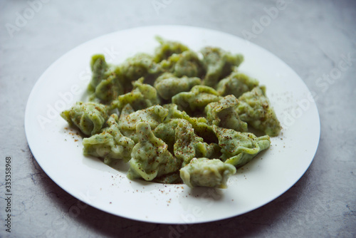 boiled dumplings in a spinach dough with pepper on white dish
