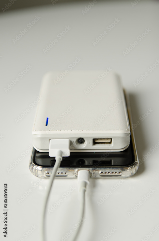 Smartphone charging with power bank on white background Smartphone charging with power bank on white background