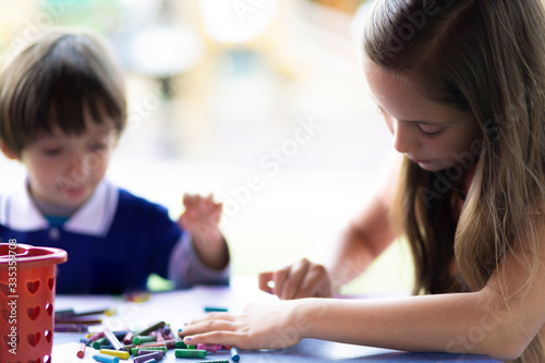 Cute Girl and Boy Sitting at his Desk Painting