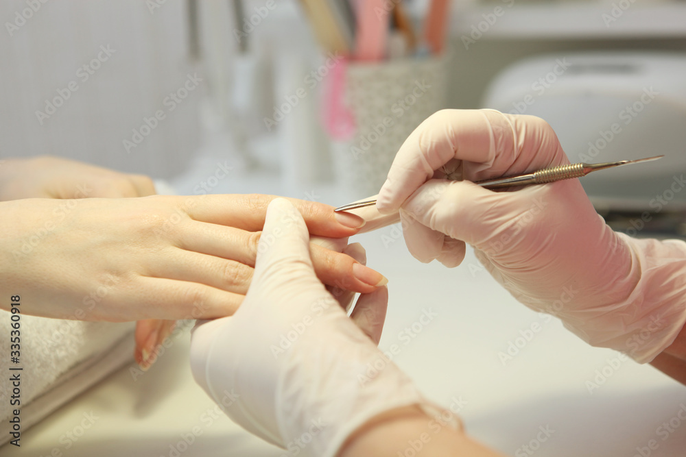 Closeup shot of a woman in a nail salon getting a manicure by a cosmetologist with a nail file. Woman gets a manicure of nails. Beautician puts nails on the client.
