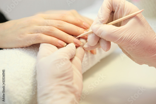 Closeup shot of a woman in a nail salon getting a manicure by a cosmetologist with a nail file. Woman gets a manicure of nails. Beautician puts nails on the client. 
