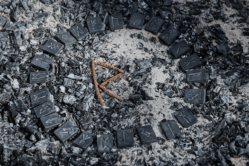 Norse rune Raidho on ashes backgorund inside the circle of 24 Norse runes photo