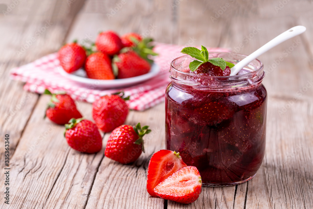 Homemade delicious strawberry jam and strawberry on a rustic wooden table Homemade delicious strawberry jam and strawberry on a rustic wooden table
