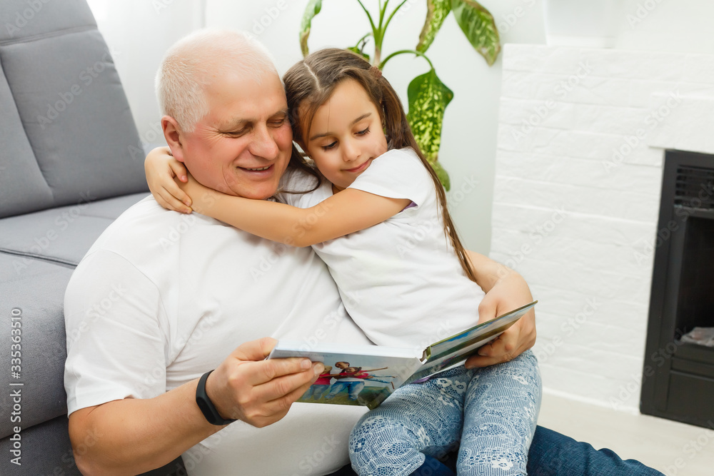 Φωτογραφία Happy little girl with grandfather watching photo books at home