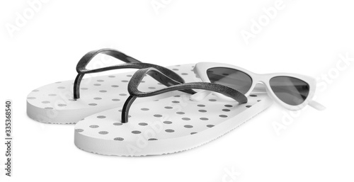 Stylish flip flops and sunglasses on white background