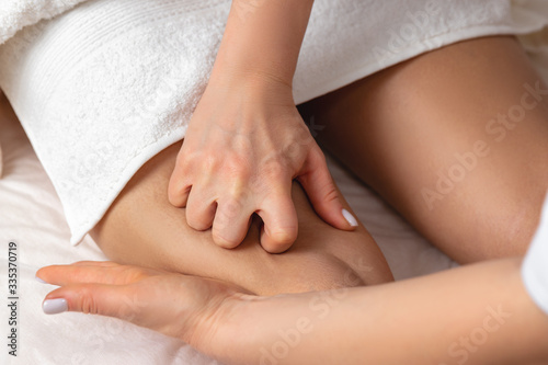 Close-up female masseur hands making thigh massage. Body care in spa salon for young woman. Beautiful girl enjoying treatment procedure  concept of body care and cosmetology