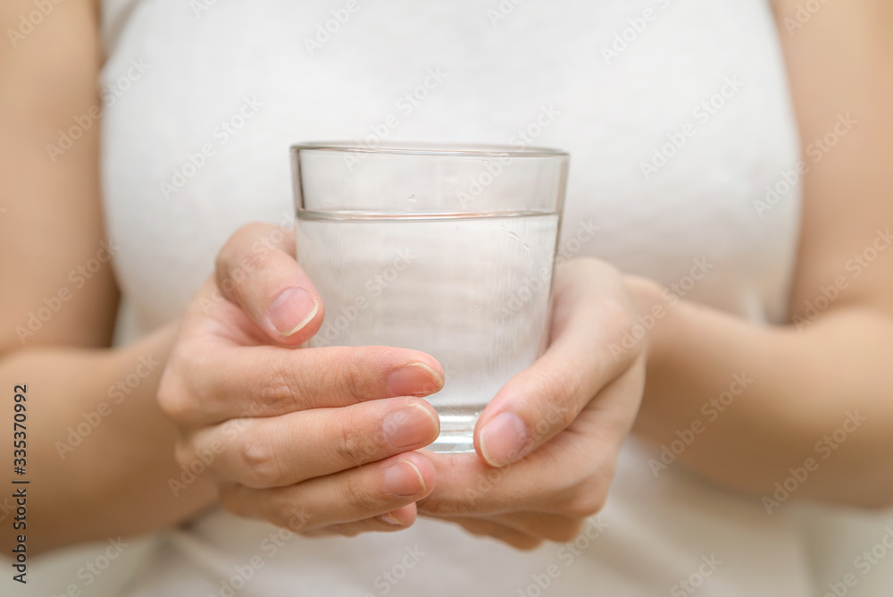 a healthy young woman holds a glass of water. clean drinking water in a clear glass in your hands close-up. water filter a healthy young woman holds a glass of water. clean drinking water in a clear glass in your hands close-up. water filter