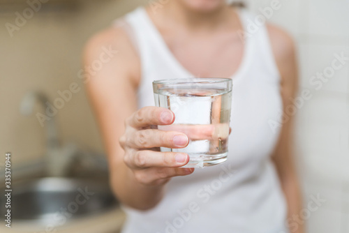 a healthy young woman holds a glass of water. clean drinking water in a clear glass in your hands close-up. water filter