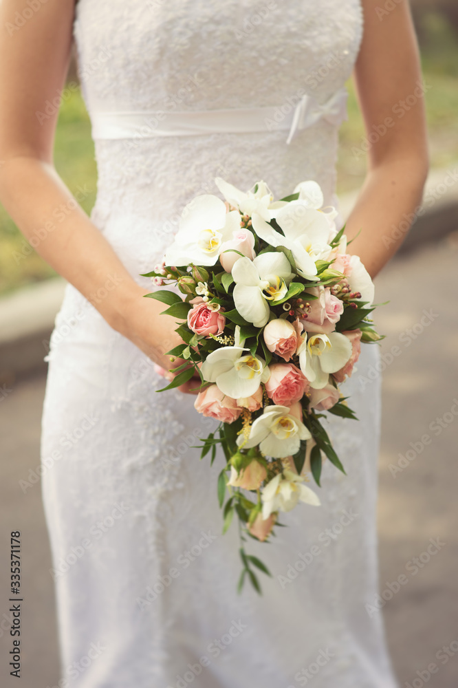 Bride in white dress holds a beautiful bouquet cascade Bride in white dress holds a beautiful bouquet cascade