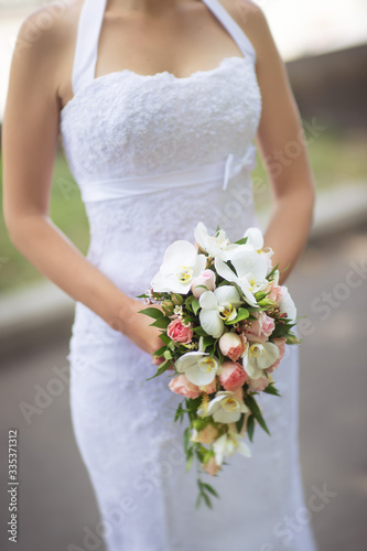 Bride in white dress holds a beautiful bouquet cascade
