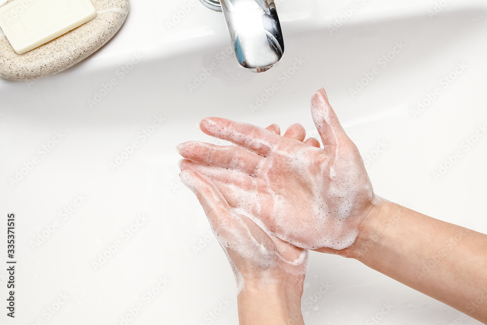 Fototapeta premium A Hands with soap are washed under the tap with water. Clean from infection and dirt and virus. At home or in the hospital ablution office.