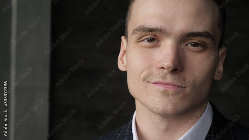 Handsome serious face of thoughtful 20s business person in suit looks at camera closeup indoors. Head shoulders portrait of one happy young successful confident pretty ceo posing single at work place