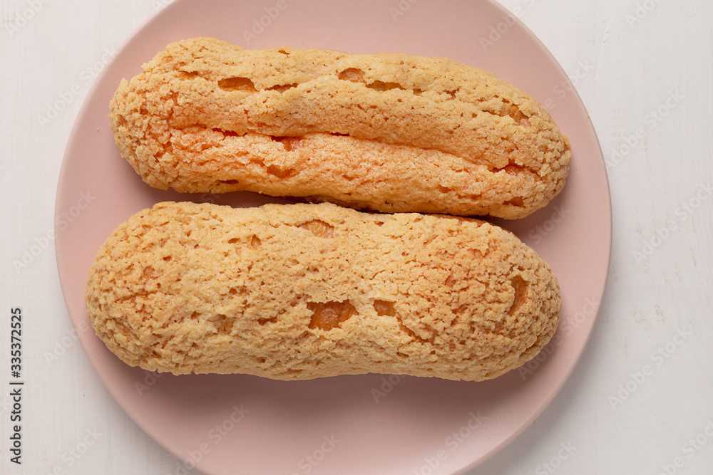 Eclair on the plate. Light pastel background. Dessert. concept, minimalism Eclair on the plate. Light pastel background. Dessert. concept, minimalism