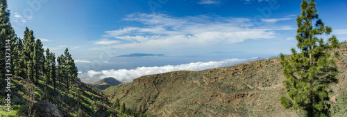 Super wide angle panoramic view of the west side of Tenerife Island. Hiking by the mountain trail surrounded by endemic vegetation and fields of lava rocks. Canary Islands, Spain