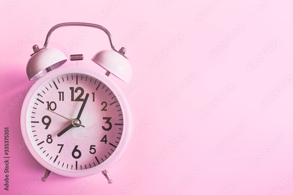 Pink alarm clock lying on pink