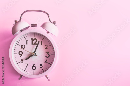 Pink alarm clock lying on pink