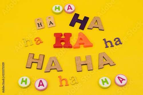 Ha, ha, ha, laugh made with letters of different colors, sizes and materials on yellow background photo