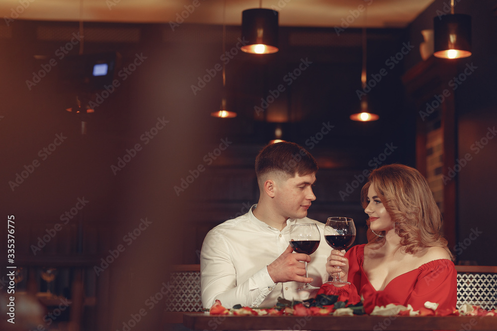 Couple in a restaurant. Lady in a red dress. Pair drinking a vine. Valentine's day.