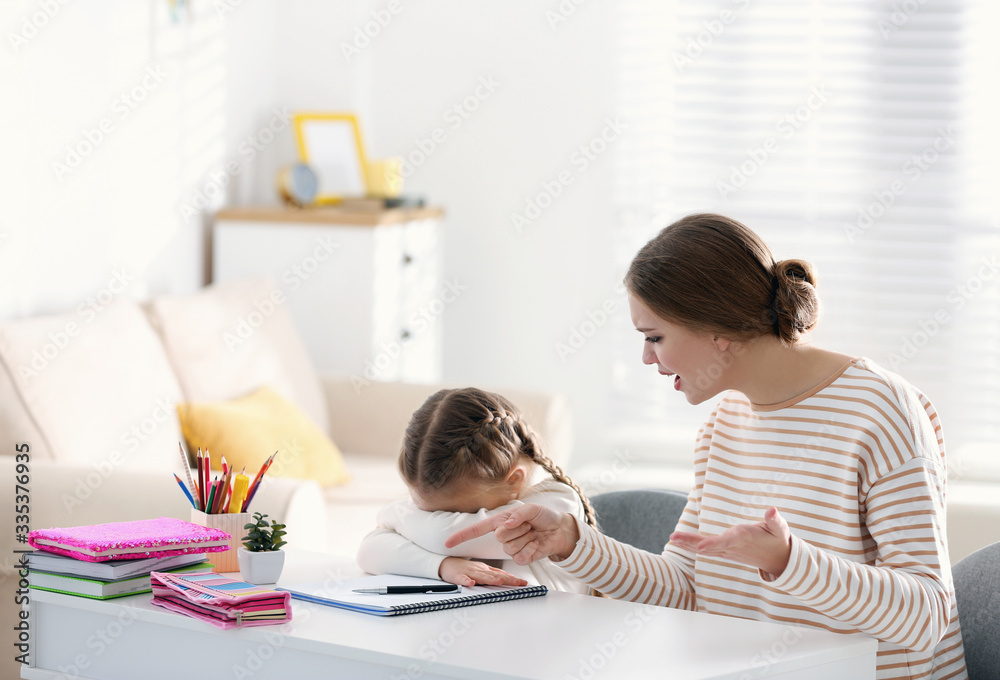 Mother scolding her daughter while helping with homework indoors Mother scolding her daughter while helping with homework indoors