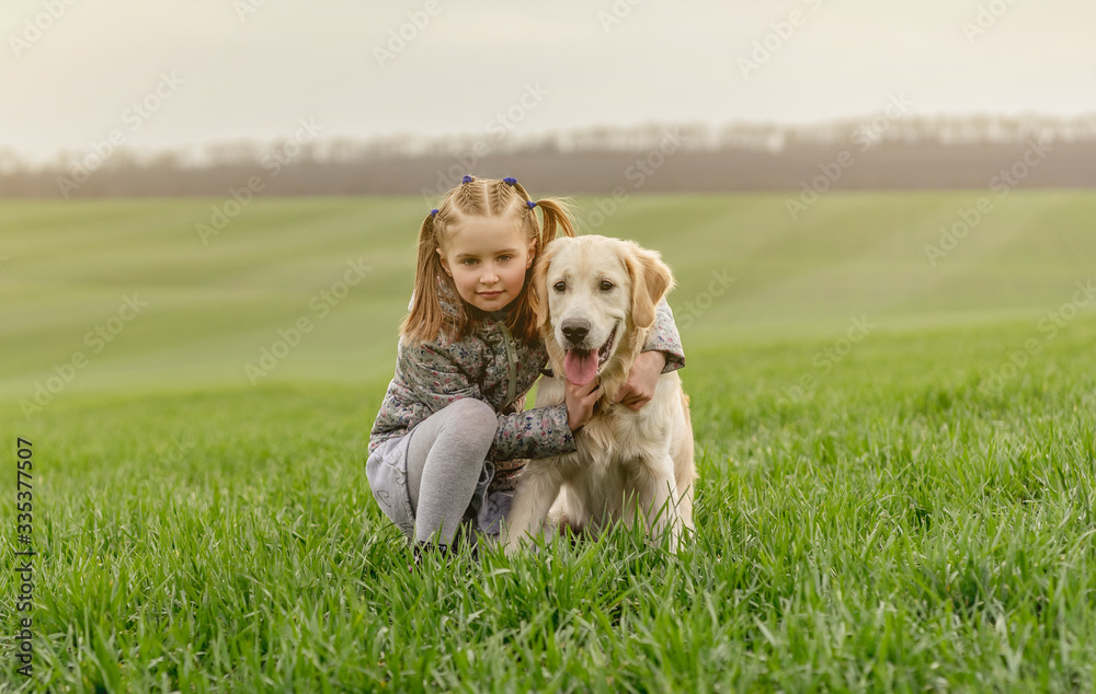 Little girl cuddling dog on field