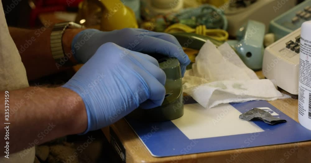 Man hand polishing old telephone on work bench - close up on hands Man hand polishing old telephone on work bench - close up on hands