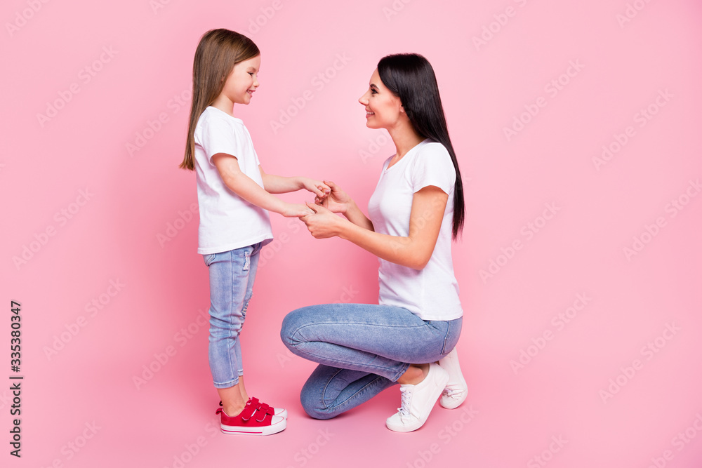 Profile side view portrait of two nice attractive lovely cute affectionate careful cheerful cheery sisters holding hands speaking contact growing up upbringing isolated on pink pastel color background Profile side view portrait of two nice attractive lovely cute affectionate careful cheerful cheery sisters holding hands speaking contact growing up upbringing isolated on pink pastel color background