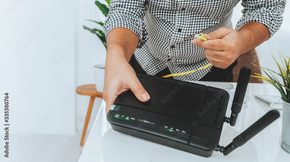 hand and lan network cable with people work on wireless router, man working  from home, while in quarantine isolation during the Covid-19 health crisis.  Stock Photo | Adobe Stock