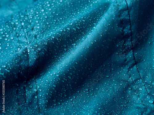 Rain water droplets on blue fiber waterproof fabric. Blue background.