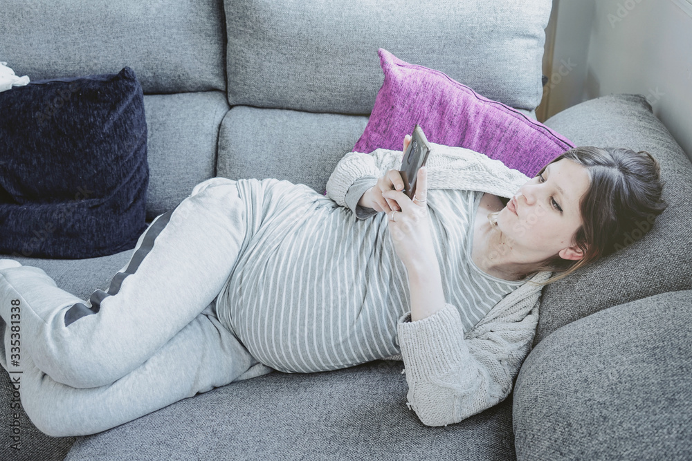 Young pregnant woman at home using her mobile phone Young pregnant woman at home using her mobile phone