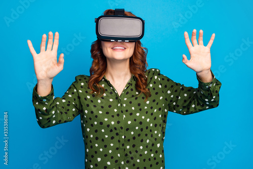Photo of pretty crazy lady raise hands watch space galaxy planets show in vr box goggles try to touch cosmic ship wear green dotted shirt isolated blue color background