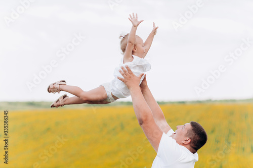 Happy daughter with daddy in the sunflower field. happy family having fun in the field of sunflowers. Dad throws his daughter in a field with sunflowers. family concept