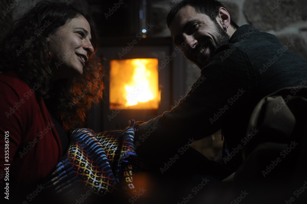 man and woman, in love couple, chat, laugh, have fun, while sheltering in the heat of a wood stove in winter in a stone country house in winter man and woman, in love couple, chat, laugh, have fun, while sheltering in the heat of a wood stove in winter in a stone country house in winter