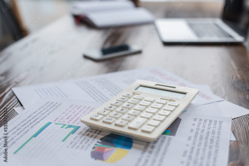 Calculator with papers on table in office Calculator with papers on table in office