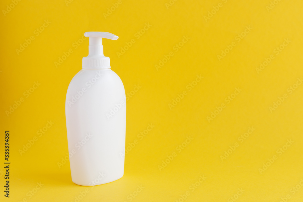 A white plastic bottle with a dispenser for liquid soap, cream or disinfectant is on a yellow background. Copy space A white plastic bottle with a dispenser for liquid soap, cream or disinfectant is on a yellow background. Copy space