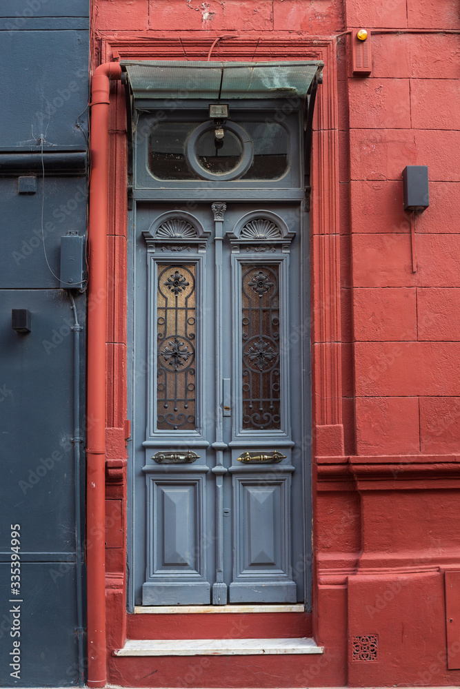 Obraz premium old textural door in grey and fragment of house facade in red