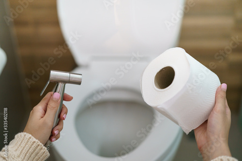 Woman make a choice, bidet shower or toilet paper. photo
