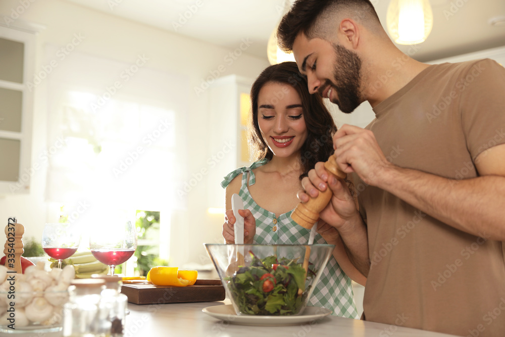 Lovely young couple cooking salad together in kitchen