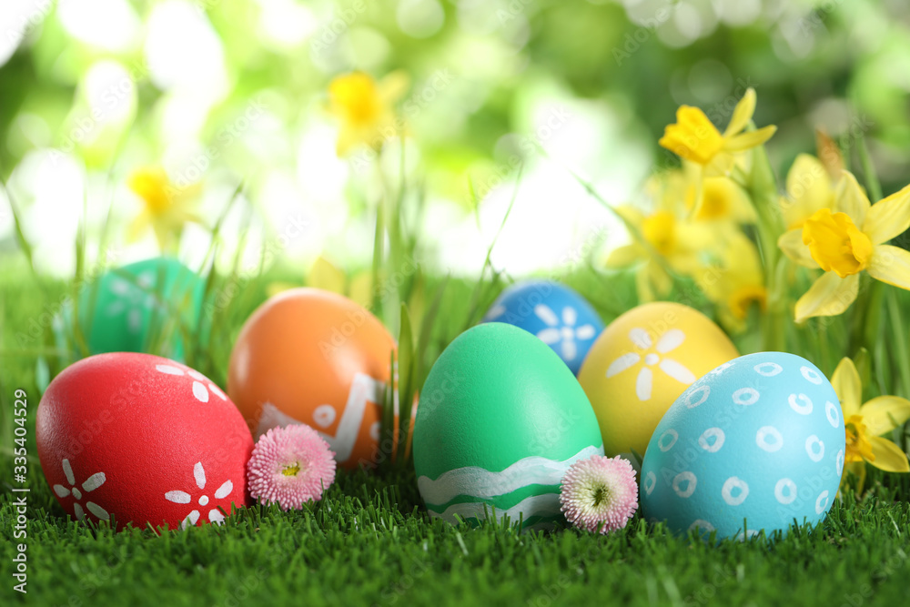 Colorful Easter eggs and flowers in green grass. Space for text Colorful Easter eggs and flowers in green grass. Space for text