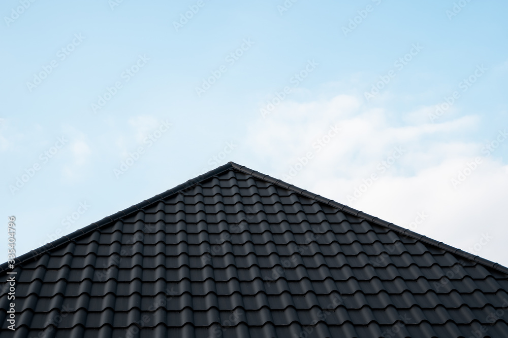 Black metal tile roof. Roof metal sheets. Modern types of roofing materials. Roof of the house, metal roof tile against the blue sky. Building. Black metal tile roof. Roof metal sheets. Modern types of roofing materials. Roof of the house, metal roof tile against the blue sky. Building.