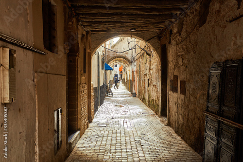 Narrow street of the old city with beige and white walls of the residential houses.