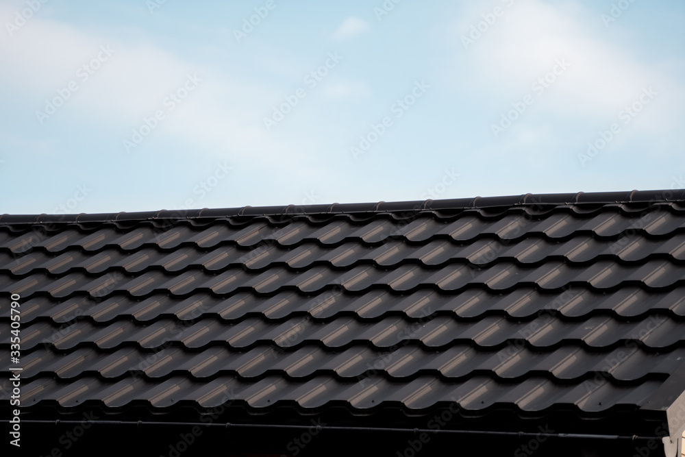 Brown metal tile roof. Roof metal sheets. Modern types of roofing materials. Roof of the house, metal roof tile against the blue sky. Building.